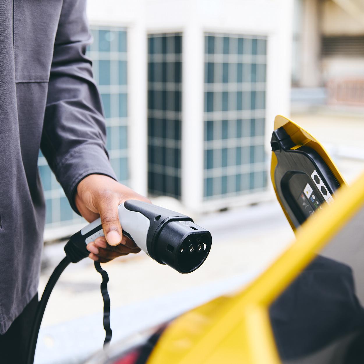 Person applying electric charger to a vehicle